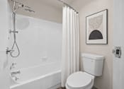 Thumbnail 38 of 87 - Bathroom with white tub shower combo and framed artwork at Village Club of Farmington Hills Apartments, Michigan