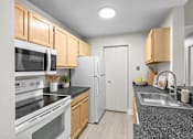 Thumbnail 41 of 87 - Galley kitchen with stainless steel sink and dark countertops at Village Club of Farmington Hills Apartments, Farmington Hills, MI