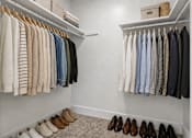Thumbnail 11 of 33 - A white closet with clothes and shoes.