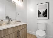 Thumbnail 10 of 33 - A bathroom with a toilet, sink, and a framed picture on the wall.