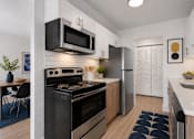 Thumbnail 2 of 33 - A modern kitchen with a black stove top oven and a black microwave above it.