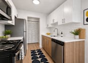 Thumbnail 1 of 33 - A modern kitchen with a black stove top oven and a black and white rug on the floor.