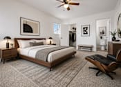 Thumbnail 15 of 33 - A bedroom with a large bed, a chair, and a ceiling fan.