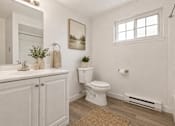 Thumbnail 20 of 35 - A white bathroom with a toilet, sink, and a window.
