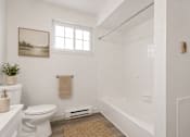 Thumbnail 35 of 35 - A white bathroom with a toilet, a sink, a window, and a rug.