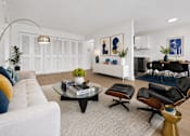 Thumbnail 4 of 33 - A living room with a white couch, a coffee table, and a dining table with chairs.
