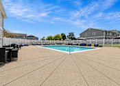 Thumbnail 21 of 33 - A large outdoor swimming pool surrounded by a concrete patio and a white fence.