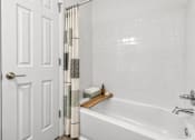 Thumbnail 23 of 29 - A white bathroom with a white tub and a white door.