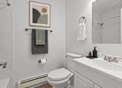 Thumbnail 21 of 29 - A bathroom with a toilet, sink, and a picture on the wall.