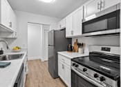Thumbnail 20 of 29 - A kitchen with a black refrigerator and stove top oven.