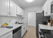 Thumbnail 18 of 29 - A modern kitchen with white cabinets and stainless steel appliances.