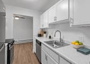 Thumbnail 17 of 29 - A modern kitchen with a stainless steel refrigerator, a sink, and wooden flooring.