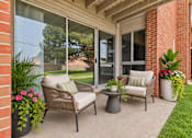 Thumbnail 9 of 29 - A patio with a chair, table, and potted plants.
