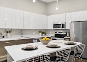 Thumbnail 2 of 64 - A modern kitchen with a white table and chairs set for a meal.