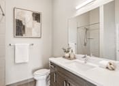 Thumbnail 4 of 64 - A bathroom with a toilet, sink, and a painting on the wall.