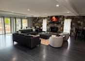 Thumbnail 29 of 38 - A modern living room with a stone fireplace and dark wood floors.