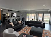 Thumbnail 30 of 38 - A modern living room with black leather sofas and a white chair.