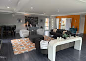 Thumbnail 28 of 38 - A modern living room with a black couch, a white chair, and a coffee table.