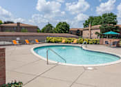 Thumbnail 33 of 38 - an oval swimming pool with orange chairs and a building in the background