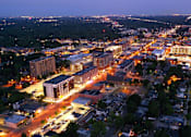 Thumbnail 1 of 31 - A cityscape at night with buildings and streets illuminated.