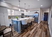 Thumbnail 3 of 31 - a kitchen with a large island with chairs and a refrigerator