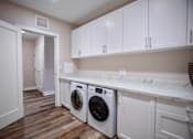 Thumbnail 9 of 31 - a washer and dryer in a laundry room with white cabinets