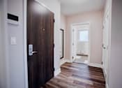 Thumbnail 14 of 31 - a wooden door leading into a room with wood floors and white walls