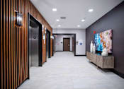 Thumbnail 29 of 31 - a hallway with elevators and a painting and a table with vases