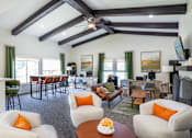 Thumbnail 23 of 35 - A living room with a white kitchen island and white chairs with orange pillows.