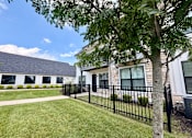 Thumbnail 20 of 39 - A black metal fence surrounds a grassy area in front of a building.