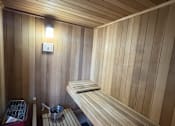 Thumbnail 25 of 31 - A wooden sauna with benches and a light on the wall.