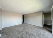 Thumbnail 4 of 35 - an empty living room with a carpeted floor and a hallway in the background
