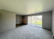 Thumbnail 8 of 35 - an empty living room with a large window and a white carpet