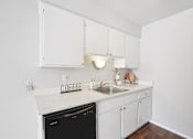 Thumbnail 18 of 45 - A small kitchen with a black dishwasher and a white counter.