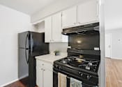 Thumbnail 19 of 45 - A black stove and refrigerator in a kitchen with white cabinets.