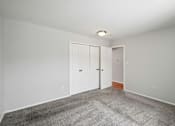 Thumbnail 20 of 45 - A room with grey carpet and white walls with two doors.