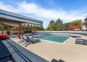 Thumbnail 56 of 73 - a swimming pool with chairs and umbrellas next to a building at Troy Place Apartments - Troy, MI, Troy, Michigan