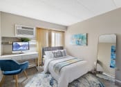 Thumbnail 39 of 73 - a bedroom with a bed and a desk with a mirror at Troy Place Apartments - Troy, MI, Troy, 48084