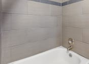 Thumbnail 46 of 73 - a white bath tub in a bathroom with tile walls at Troy Place Apartments - Troy, MI, Michigan