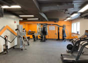 Thumbnail 54 of 73 - a gym with a row of exercise machines and a pattern on the wall at Troy Place Apartments - Troy, MI, Troy, 48084