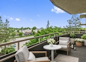 Thumbnail 25 of 31 - A balcony with a table and chairs overlooking a residential area.