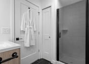 Thumbnail 8 of 38 - A white bathroom with a white robe hanging on the door.