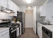 Thumbnail 6 of 24 - A kitchen with black and white appliances and wooden floors.