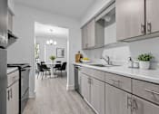 Thumbnail 11 of 38 - A modern kitchen with a dining table and chairs in the background.