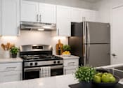 Thumbnail 3 of 24 - A modern kitchen with a black stove top and a black refrigerator.