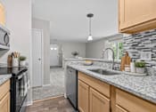 Thumbnail 17 of 87 - Kitchen with granite countertops and tile backsplash at Village Club of Farmington Hills Apartments, Michigan, 48331