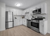 Thumbnail 1 of 14 - A modern kitchen with stainless steel appliances and white cabinetry.