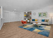 Thumbnail 6 of 38 - A living room with a white couch, a blue rug, and a white cabinet.