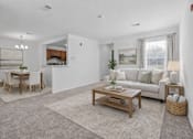Thumbnail 9 of 43 - A living room with a white couch, a wooden coffee table, and a dining table with chairs.