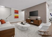 Thumbnail 5 of 14 - A modern living room with a white sofa, a white coffee table, a white rocking chair, a wooden cabinet, a flat screen TV, and a painting on the wall.